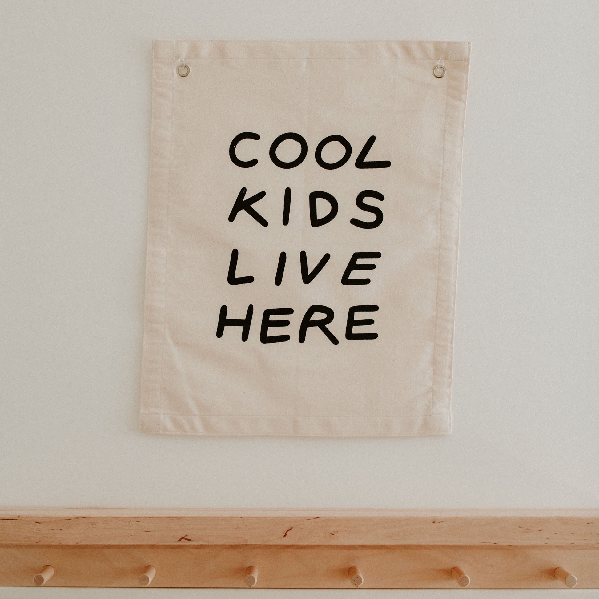 Beige banner with 'COOL KIDS LIVE HERE' text on a white wall.