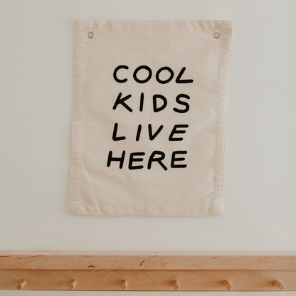 Beige banner with 'COOL KIDS LIVE HERE' text on a white wall.