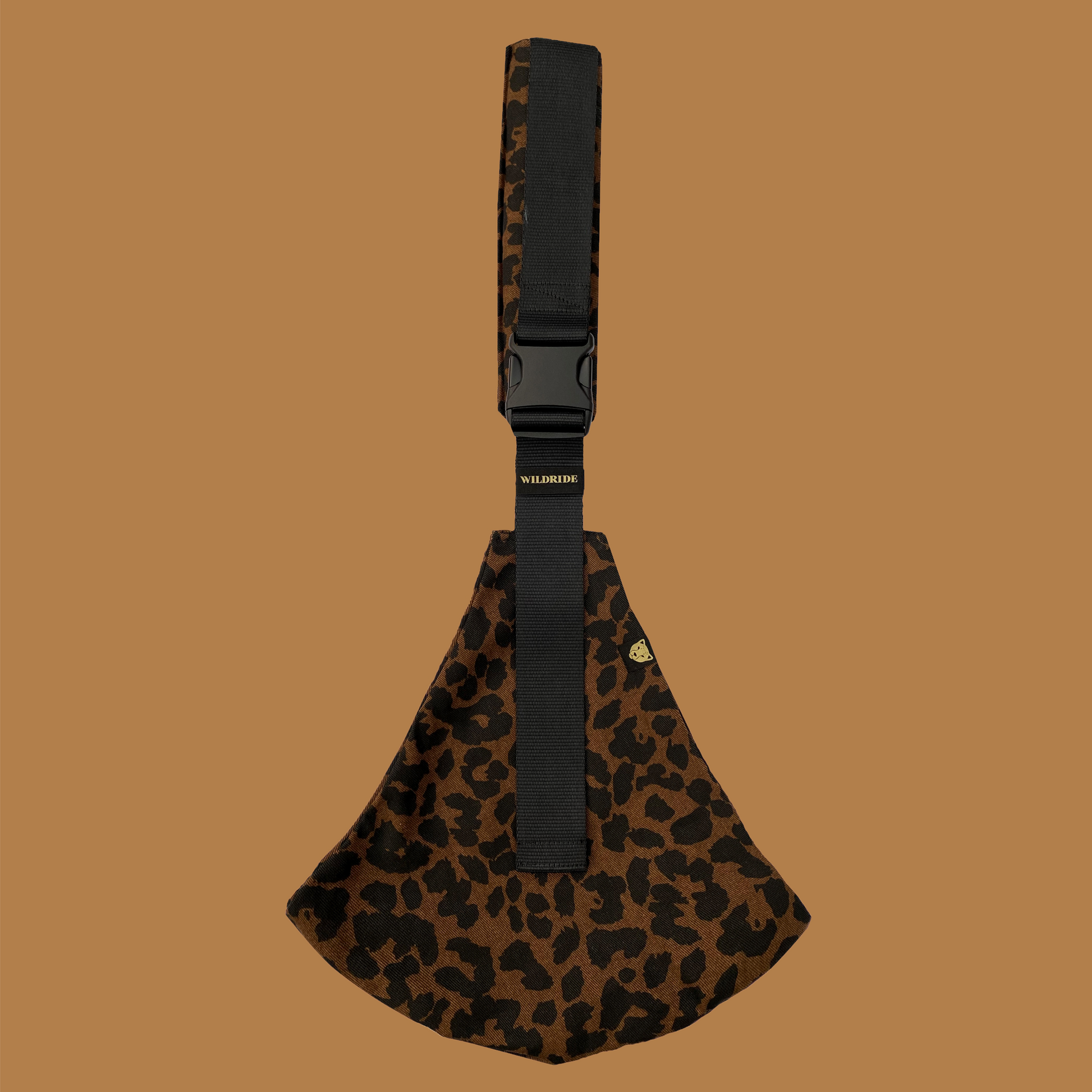 Leopard print bag with a black strap on a brown background