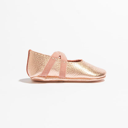 Rose gold baby shoe on a white background