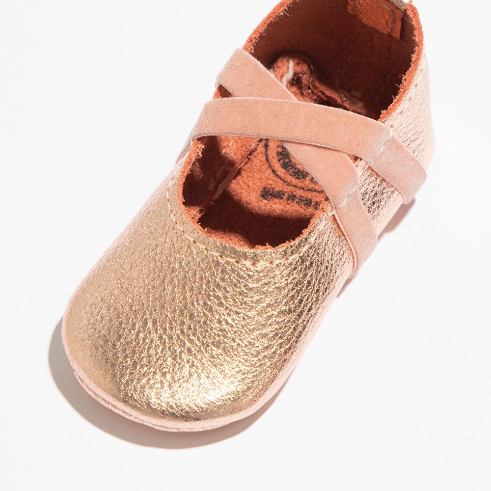 Gold children's shoe with a pink strap on a white background