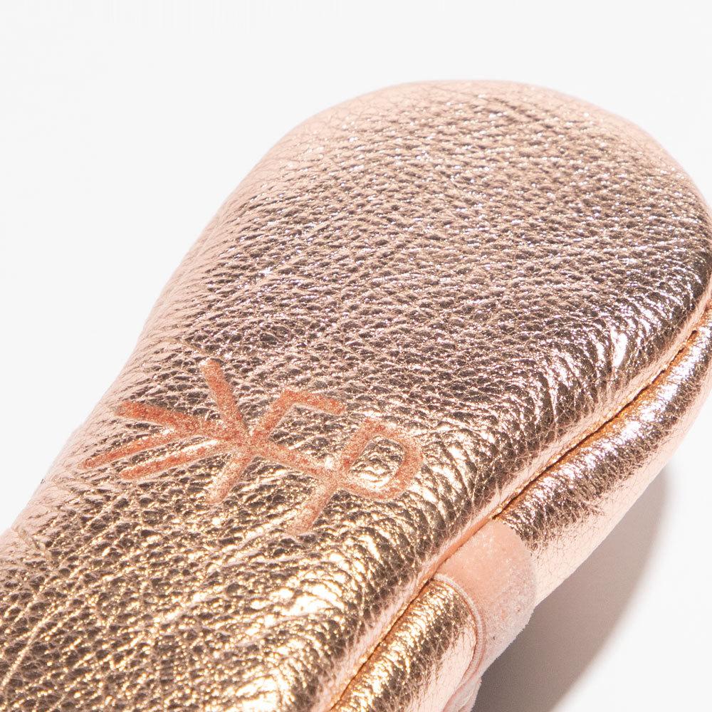 Rose gold makeup brush with brand logo on a white background