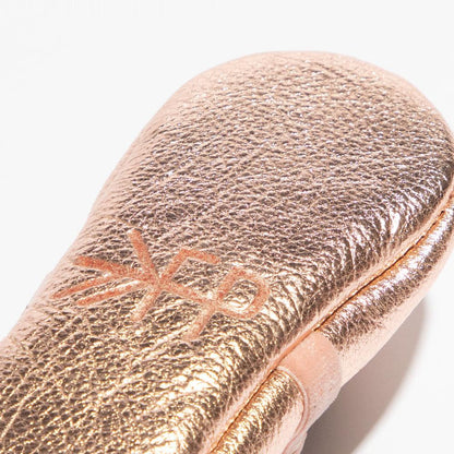 Rose gold makeup brush with brand logo on a white background