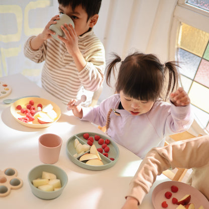Children eating snacks at a table with various food items and utensils.