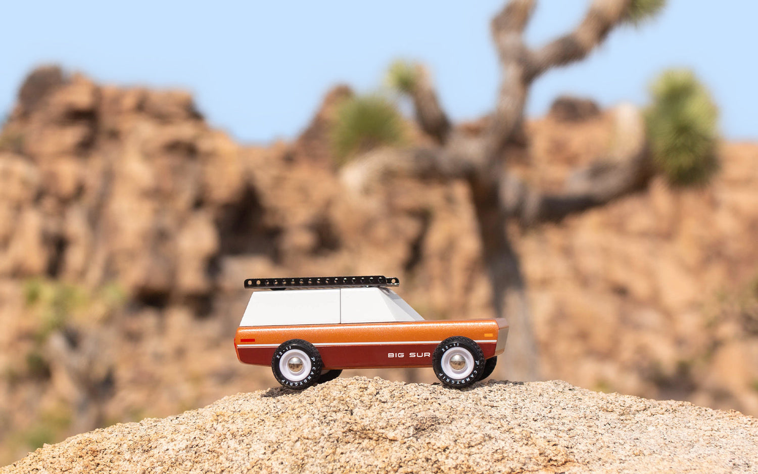Model of a vintage camper on a rock with desert landscape in the background