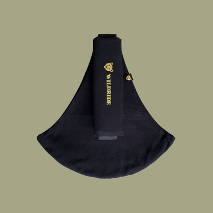 Black sling bag with gold branding on a beige background