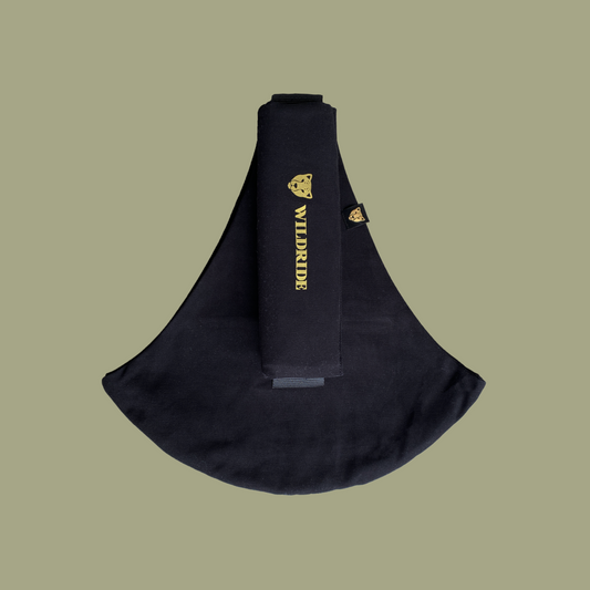 Black sling bag with gold branding on a beige background