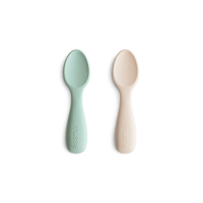 Two baby spoons, one green and one beige, on a white background