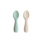 Two baby spoons, one green and one beige, on a white background