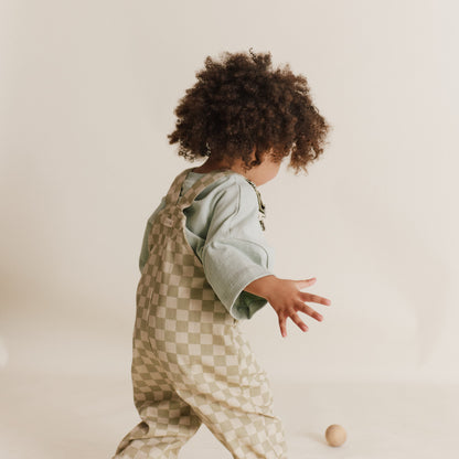 Child wearing a checkered outfit with a plain background