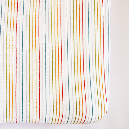 Fitted crib sheet with multicolored stripes on a white background