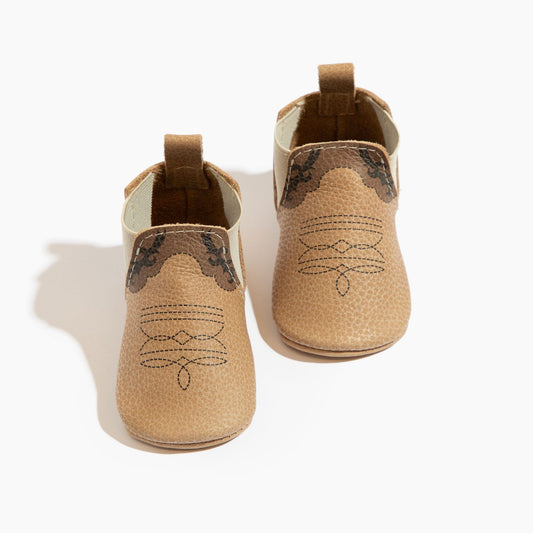 Pair of tan baby shoes with brown accents on a white background