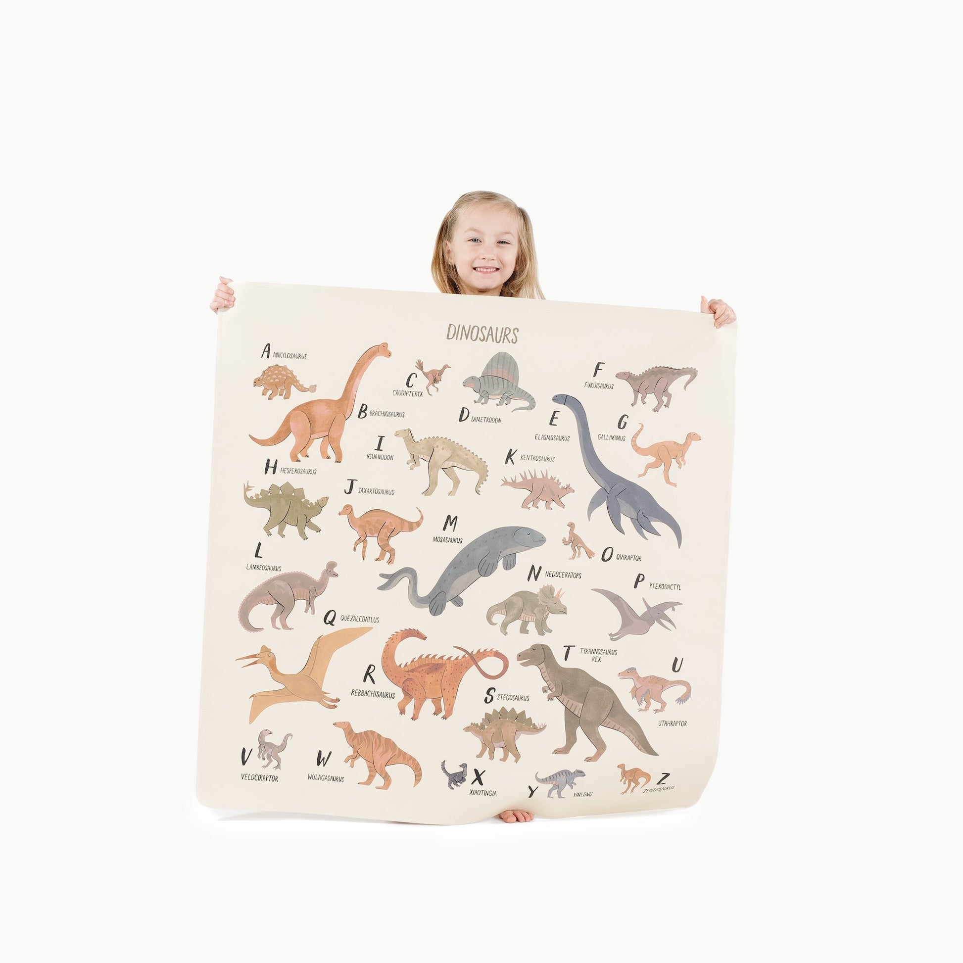 Child holding a dinosaur-themed blanket with letter matching game