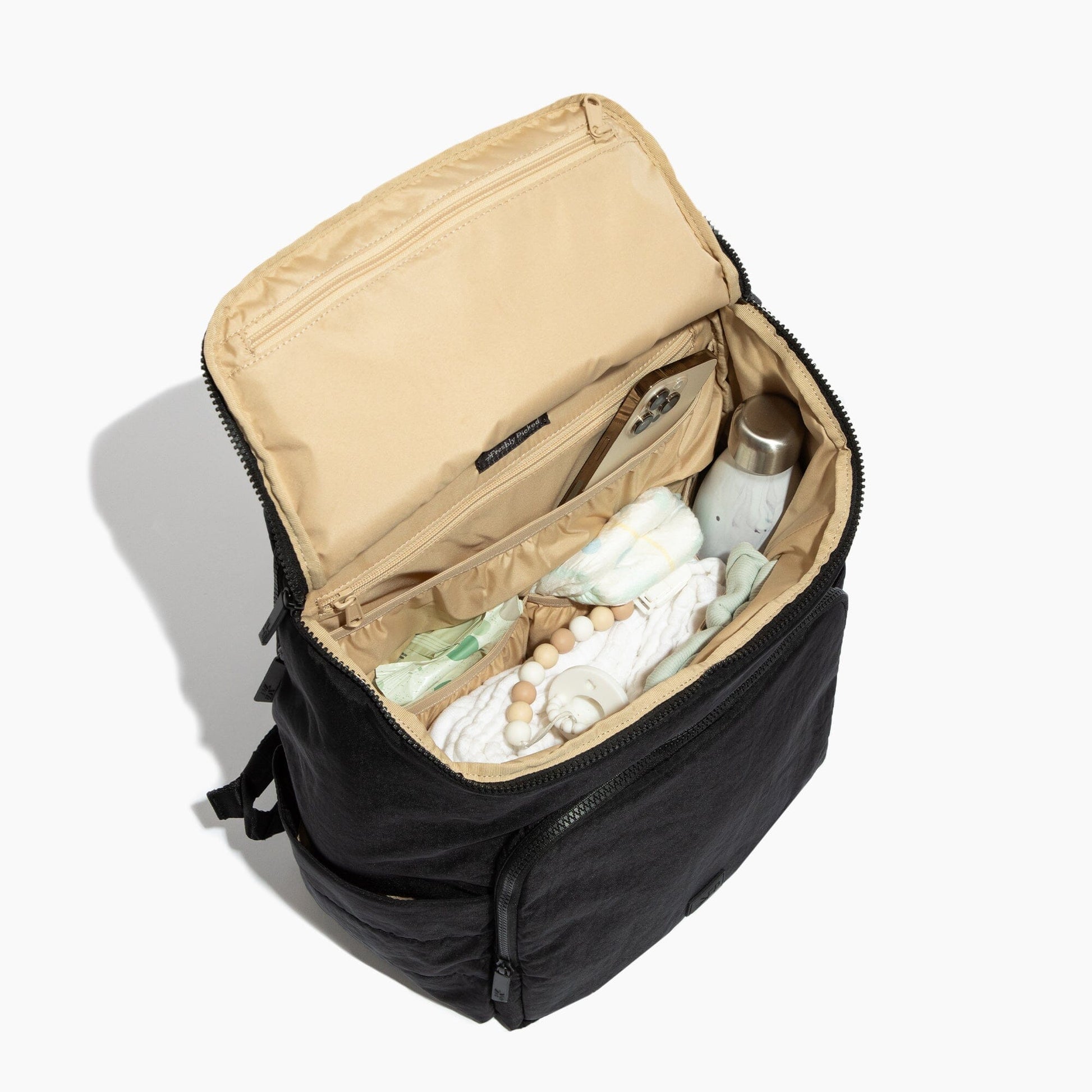 Black backpack with open compartment containing baby items on a white background