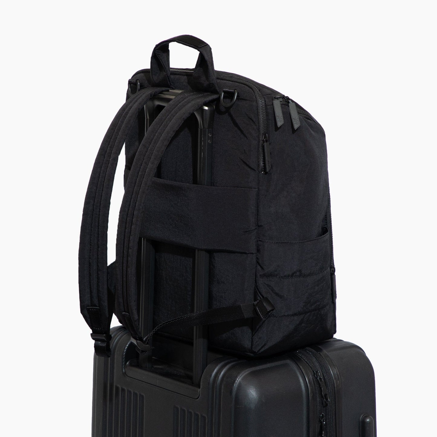 Black backpack on a suitcase against a white background