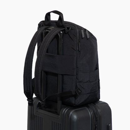 Black backpack on a suitcase against a white background