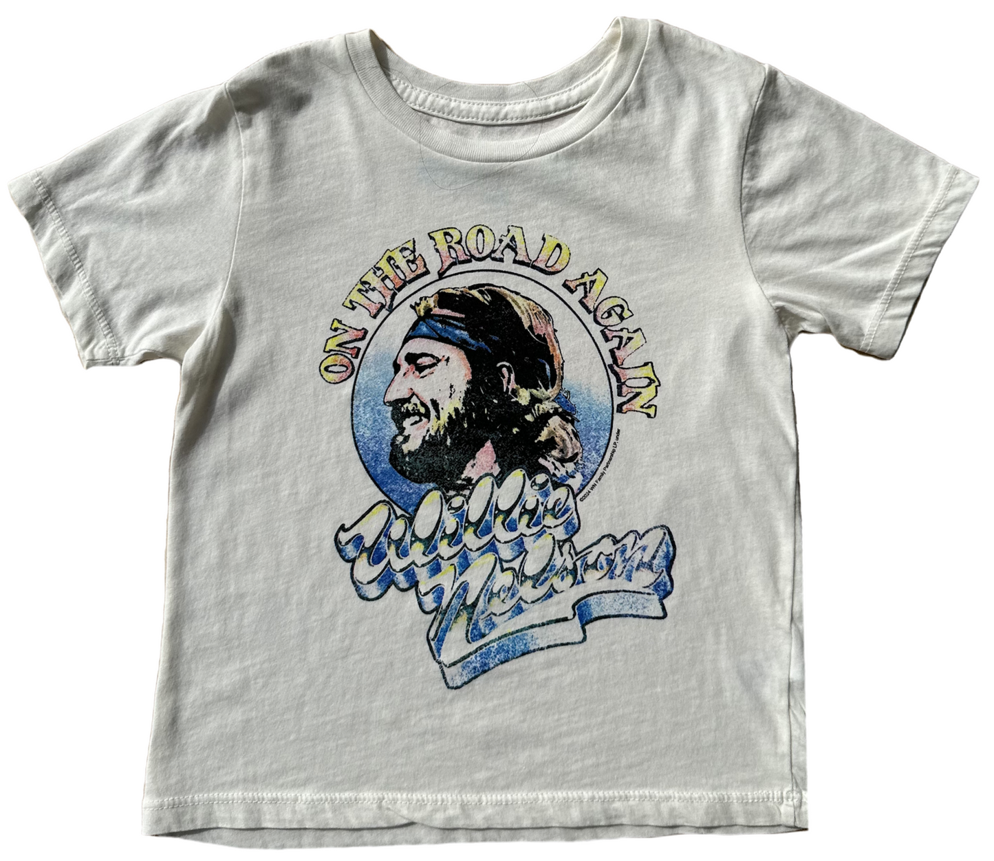 A white t-shirt with a graphic print of a male figure and the text 'On the Road Again' in a stylized font.