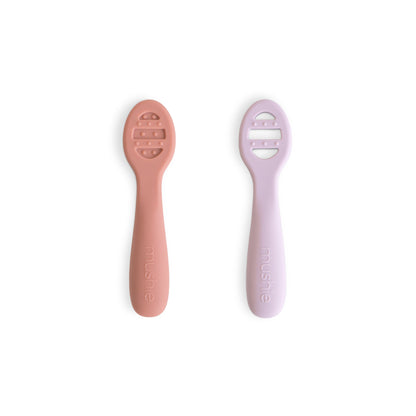 Two baby utensils, one pink and one purple, on a white background.