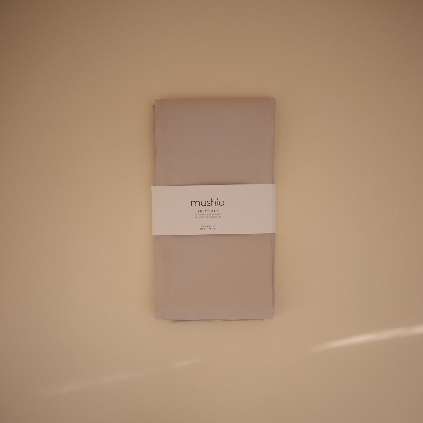 Folded beige fabric with a white label on a beige background
