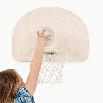 Child playing with a small basketball hoop on a white background