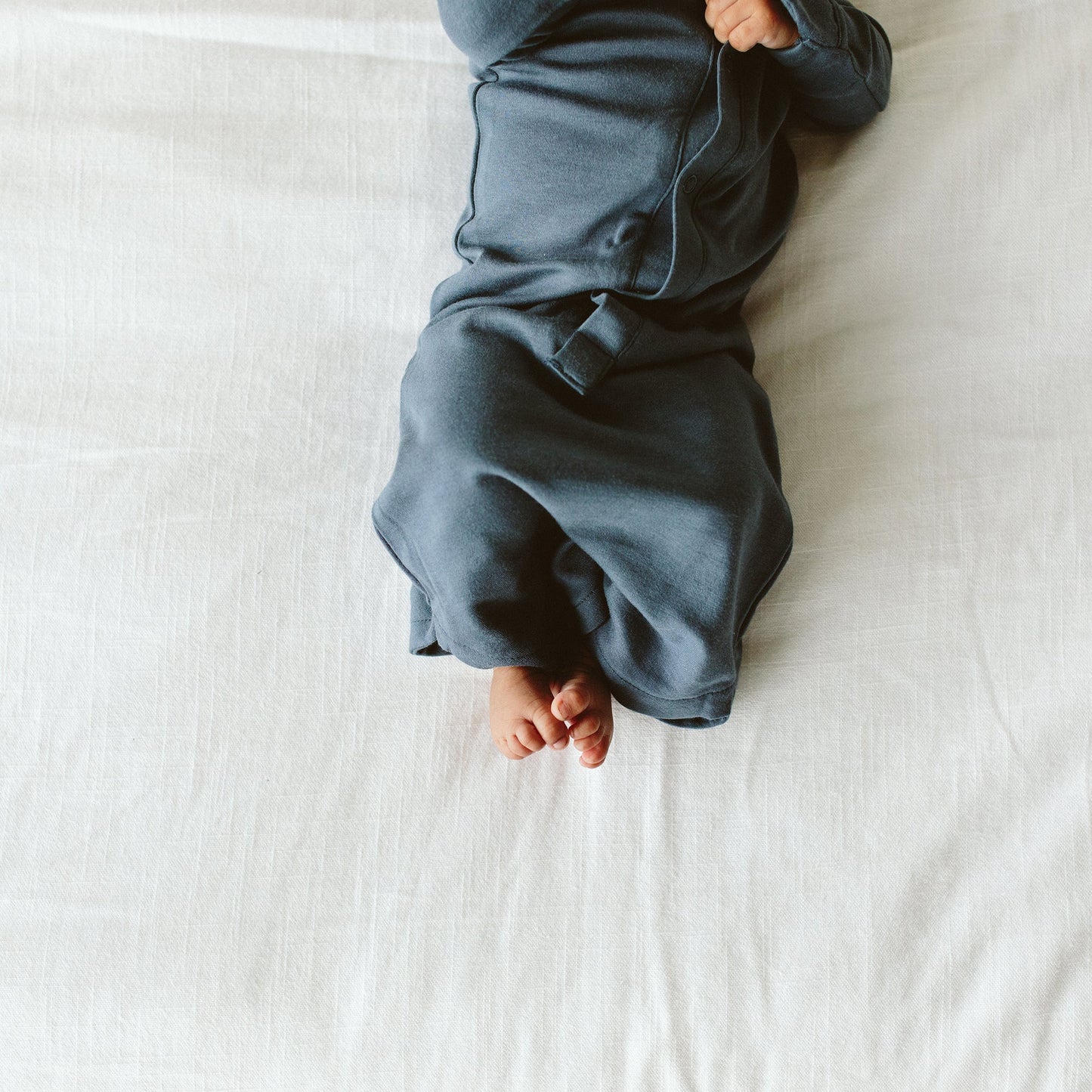 Person wrapped in a blue blanket on a white bed