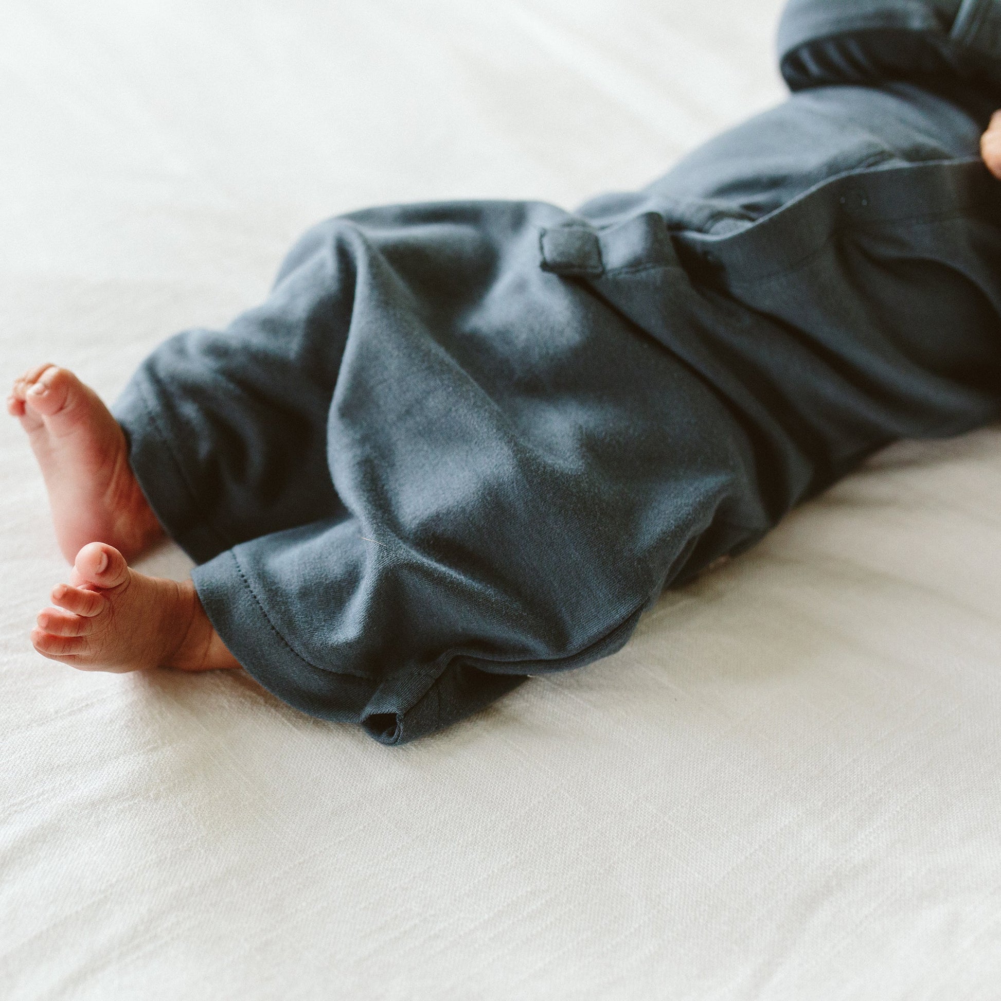 Baby's legs in blue pants on a white surface