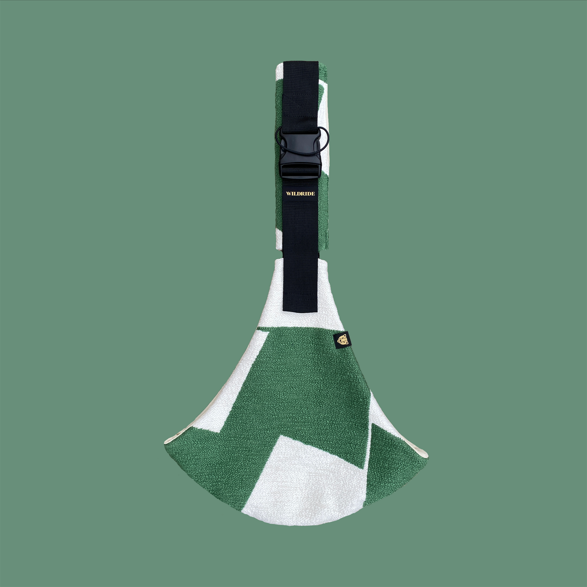 Green and white toddler carrier with a black strap on a green background