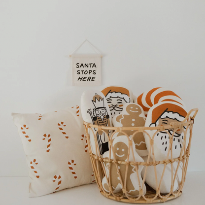 Decorative basket with Christmas-themed items including a pillow and a sign on a white background