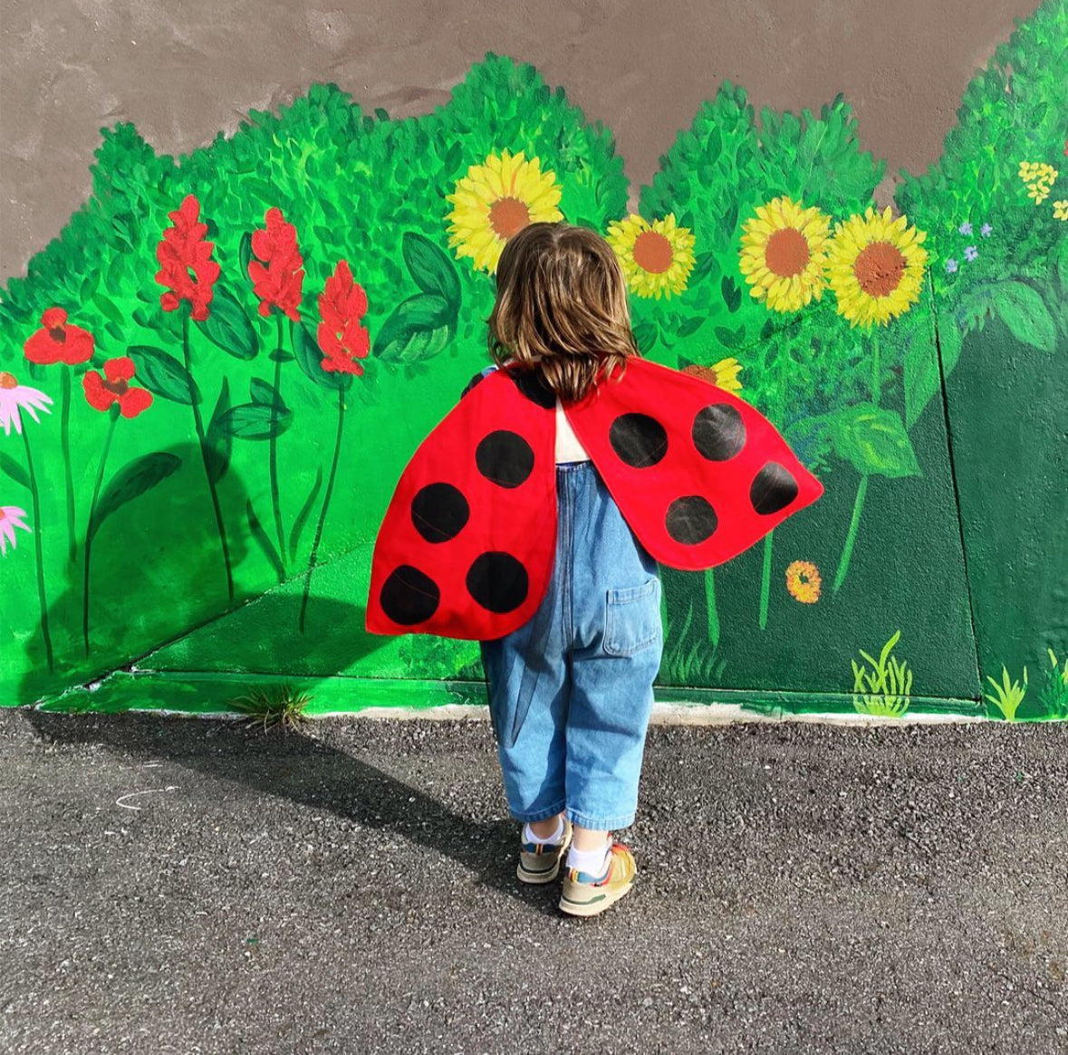 Child wearing a ladybug costume in front of a painted garden backdrop