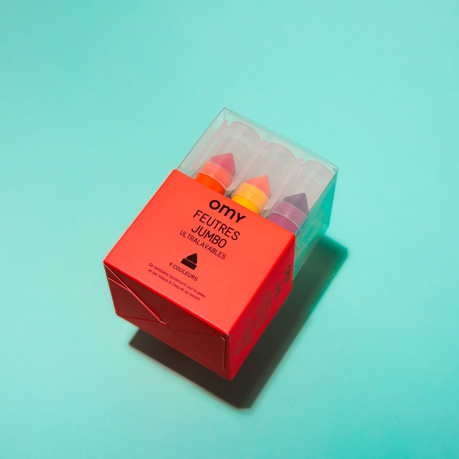 Box of OMY Jumbo crayons on a turquoise background