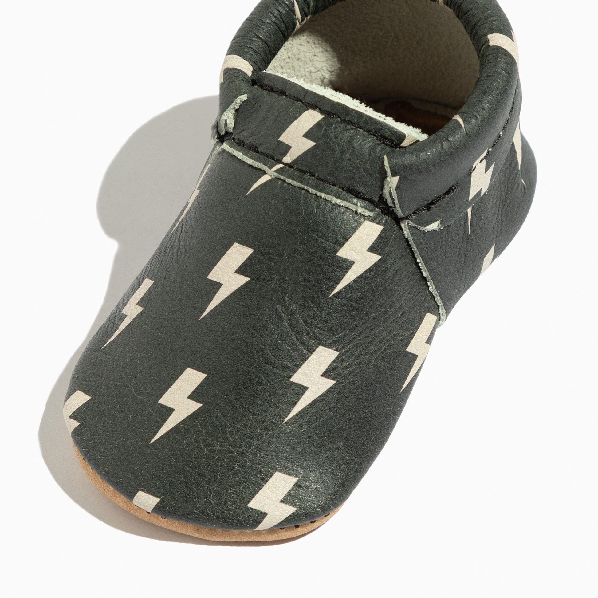 Dark gray baby shoe with white lightning bolt pattern on a white background