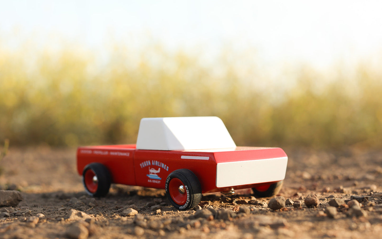 Model truck on a dirt surface with a blurred natural background