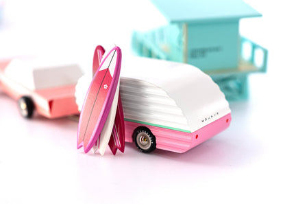 Small pink and white toy camper on a light background
