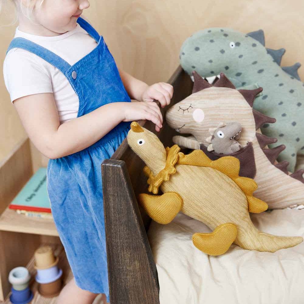Child in a blue dress playing with plush toys on a bed