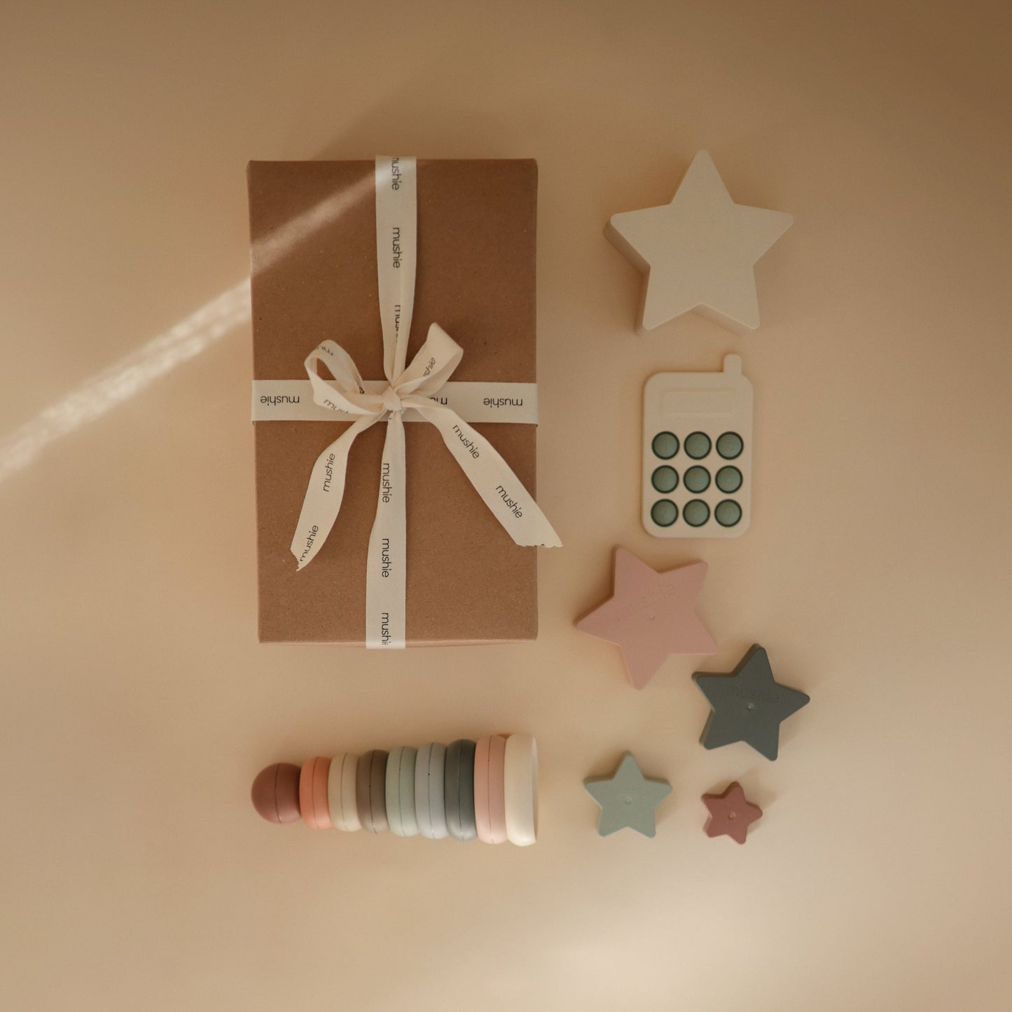 Gift box with ribbon, star-shaped decor items, and wooden rings on a beige background
