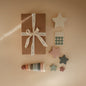 Gift box with ribbon, star-shaped decor items, and wooden rings on a beige background