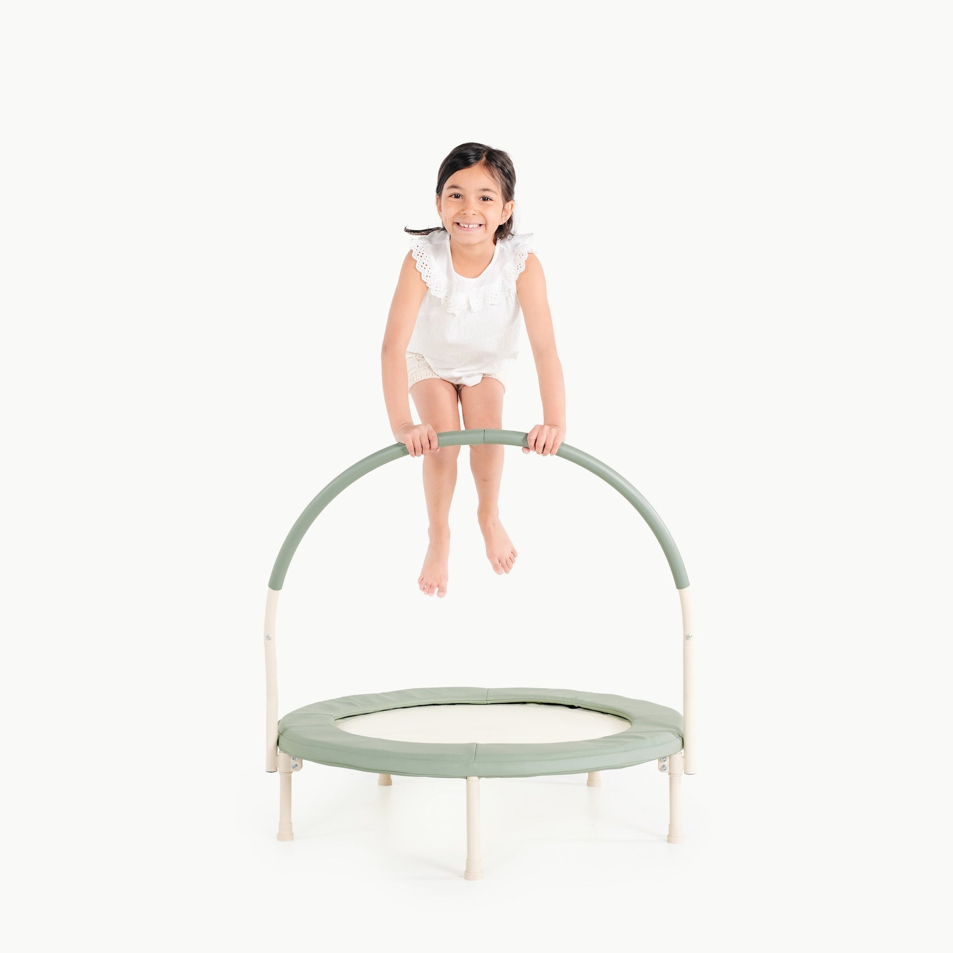 Child on a small green trampoline with a white background