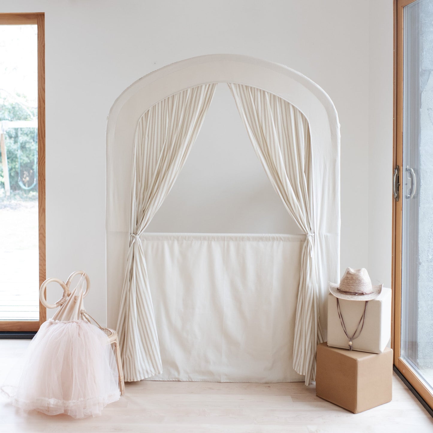 White curtain archway in a room with a window and decorative items.
