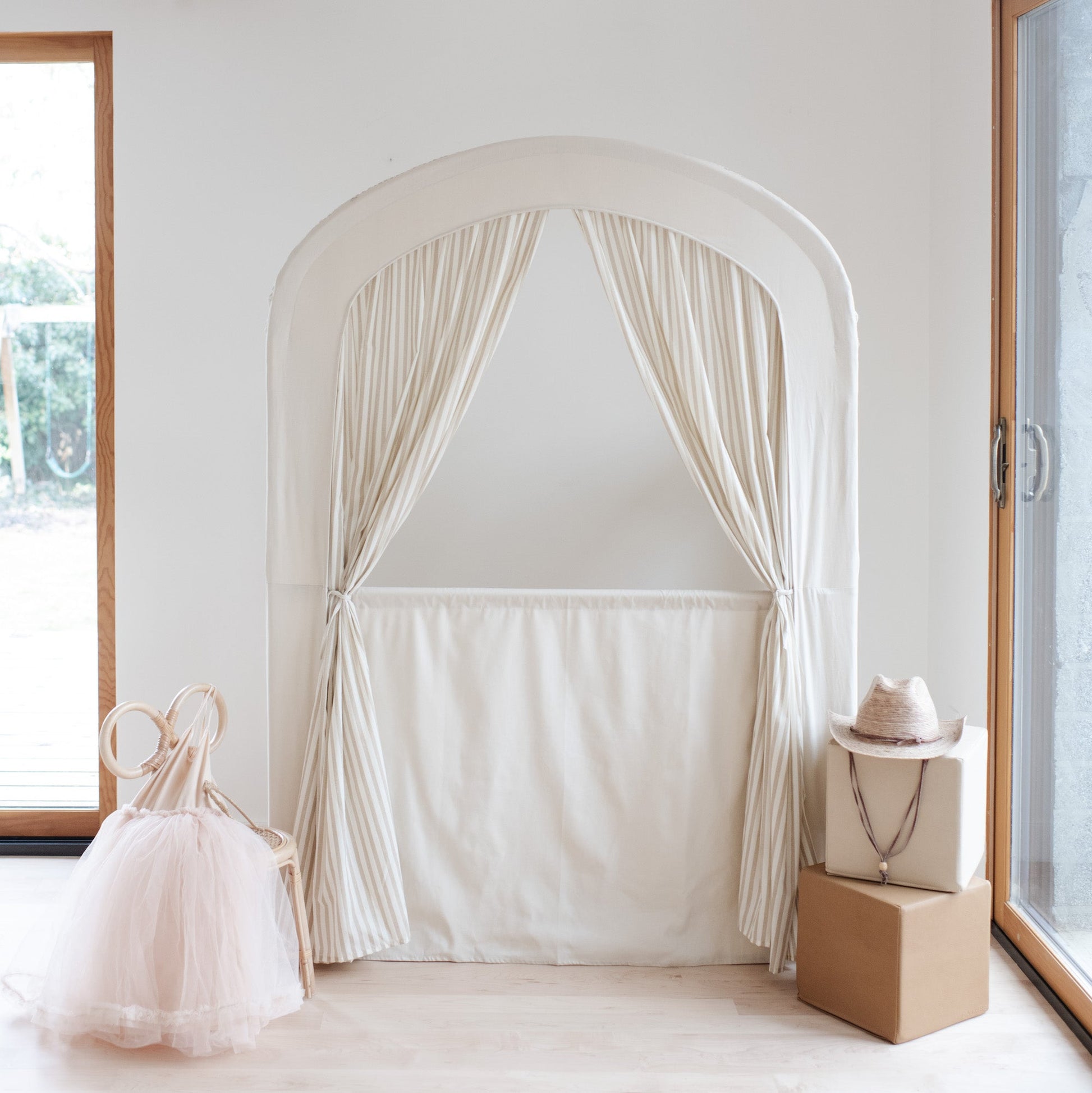 White curtain archway in a room with a window and decorative items.