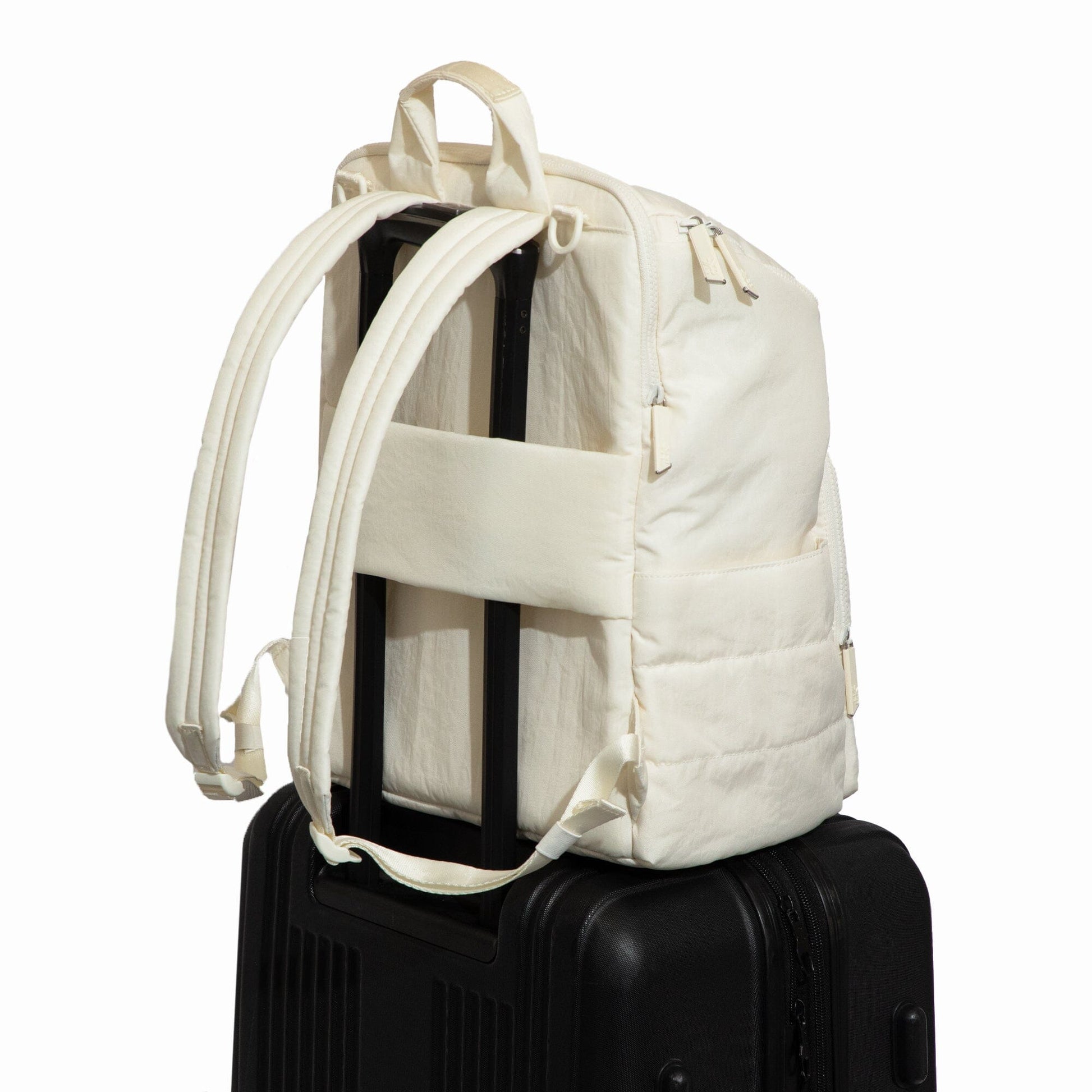 White backpack on a black suitcase against a white background