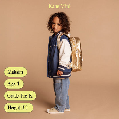 Child wearing a blue jacket and jeans with a gold backpack on a beige background, featuring the brand 'Kane Mini'.