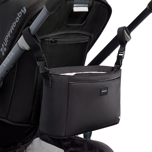 Black stroller organizer attached to a stroller on a white background