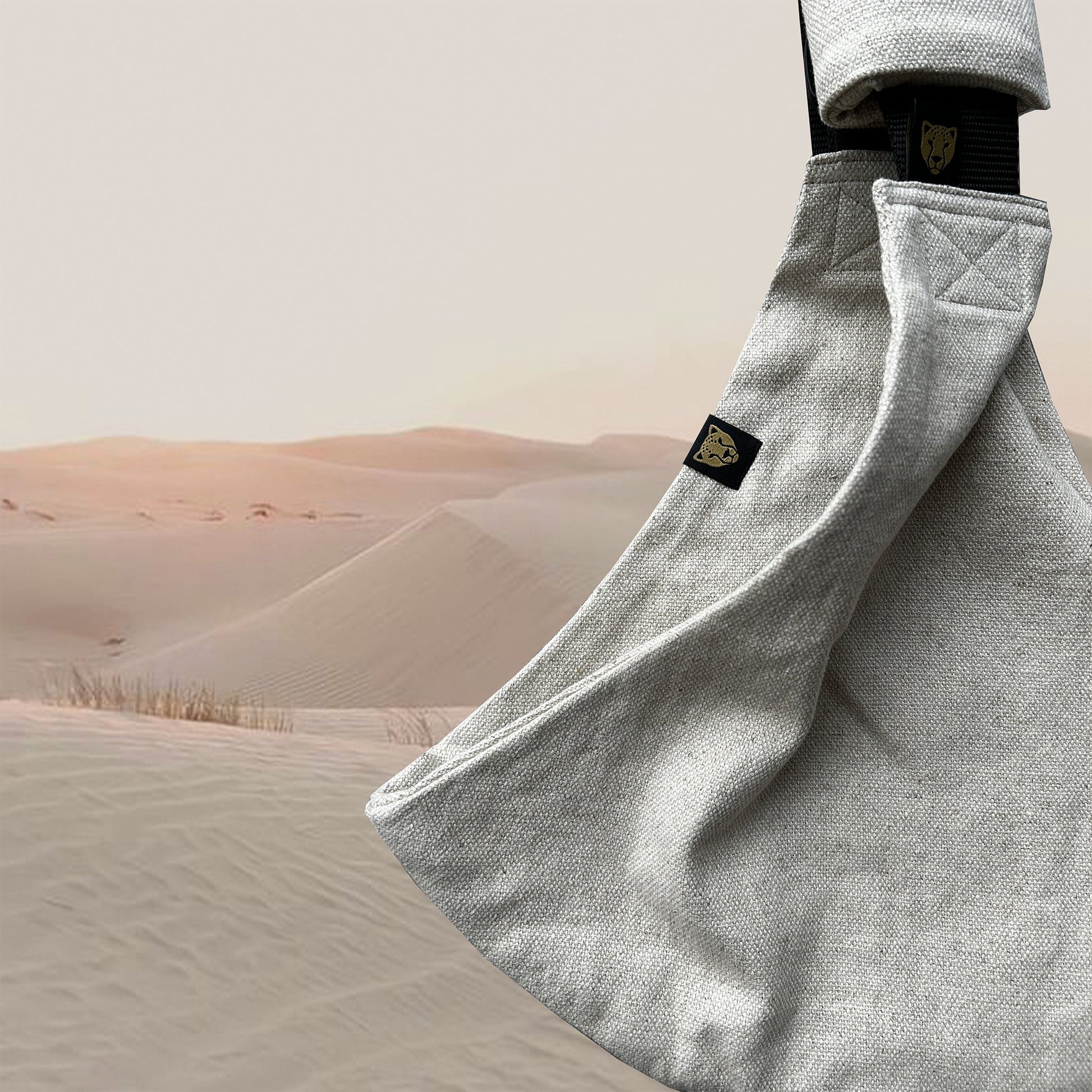 Baby carrier with a brand logo against a desert landscape