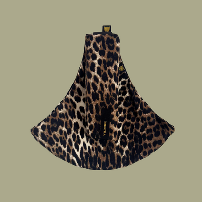 Leopard print toddler carrier on a green background