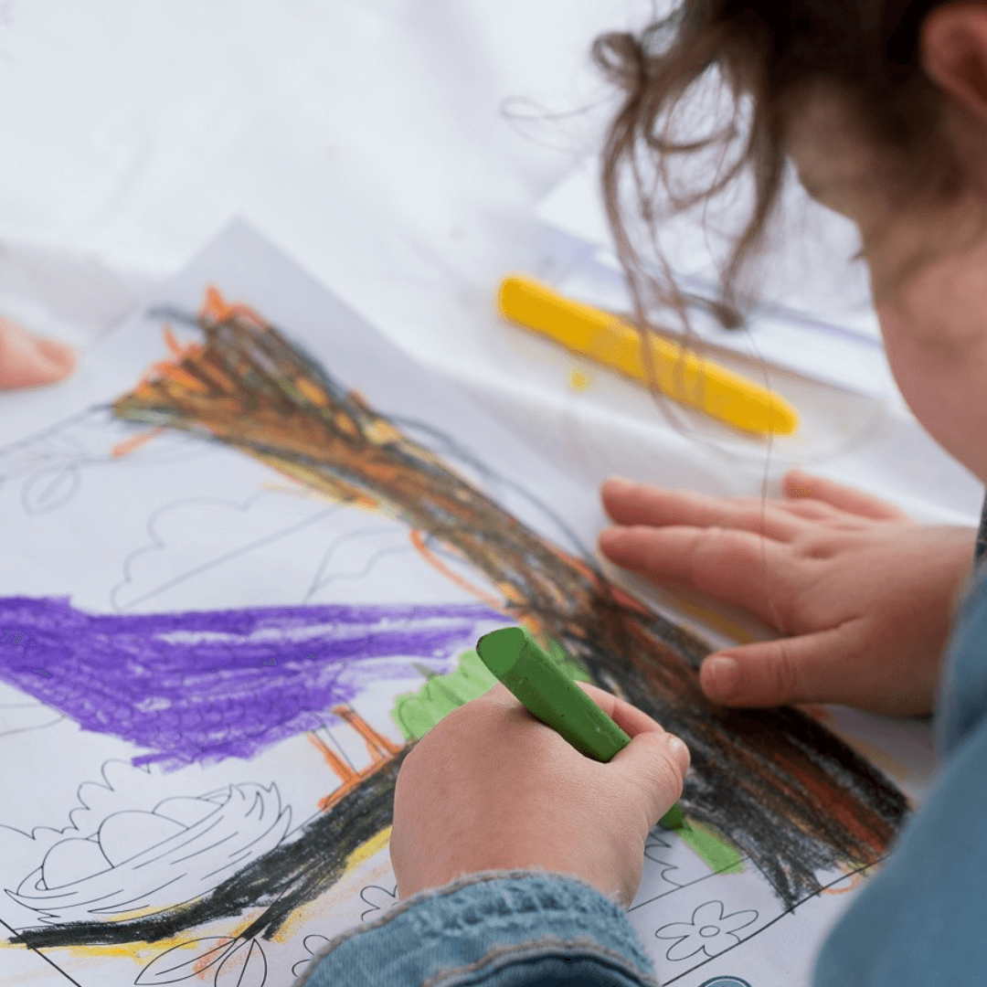 Child coloring a picture with markers on a white sheet of paper