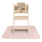 Wooden high chair with beige seat on a pink mat against a white background