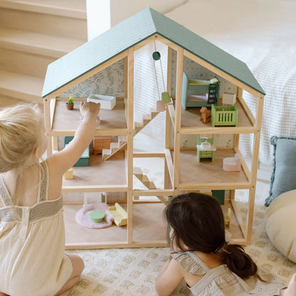 Two children playing with a wooden dollhouse in a cozy room.
