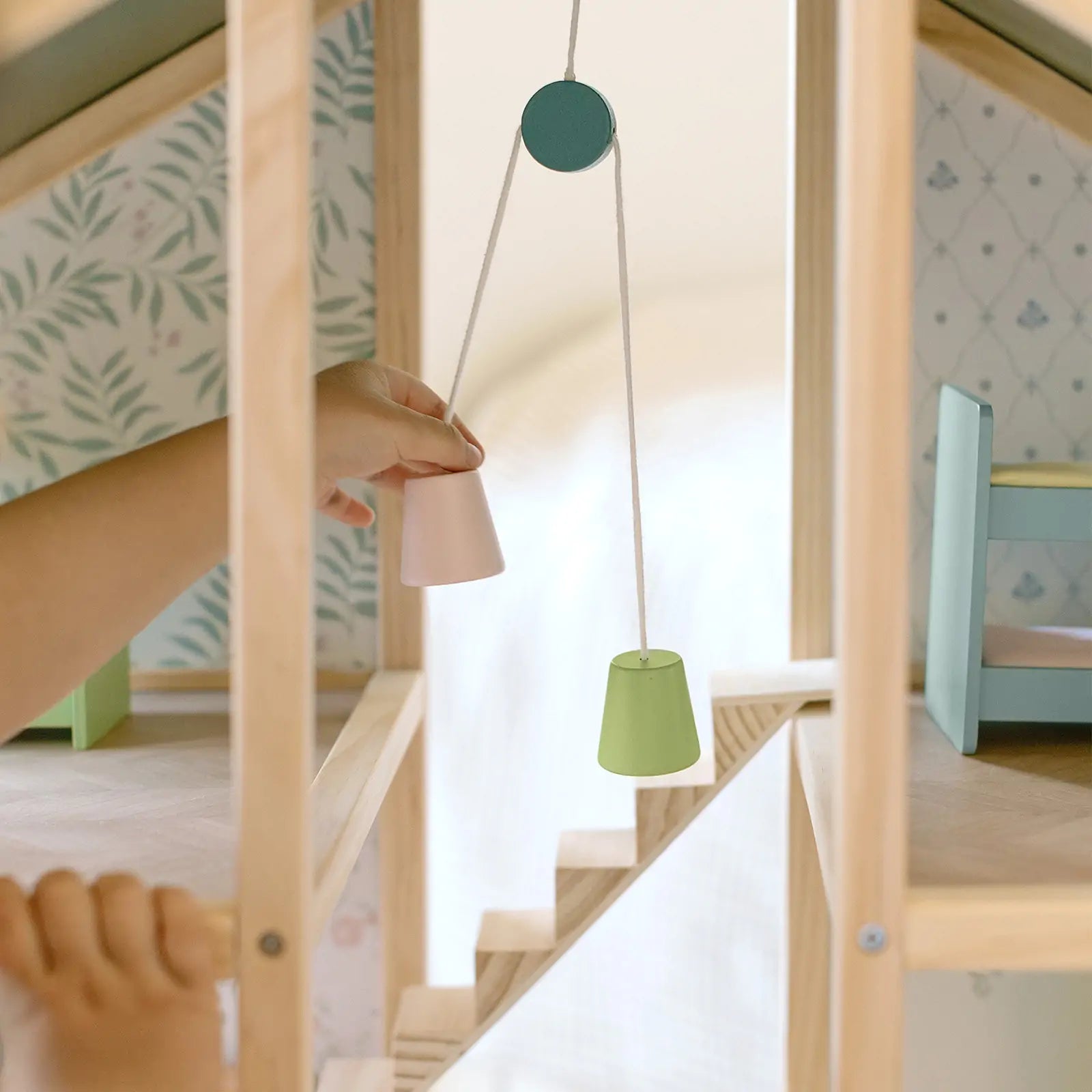 Children's room with a wooden playhouse and green hanging lamp.