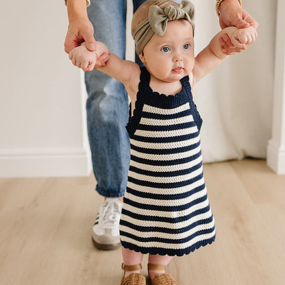 Child in a striped dress holding hands with an adult, both wearing matching outfits.