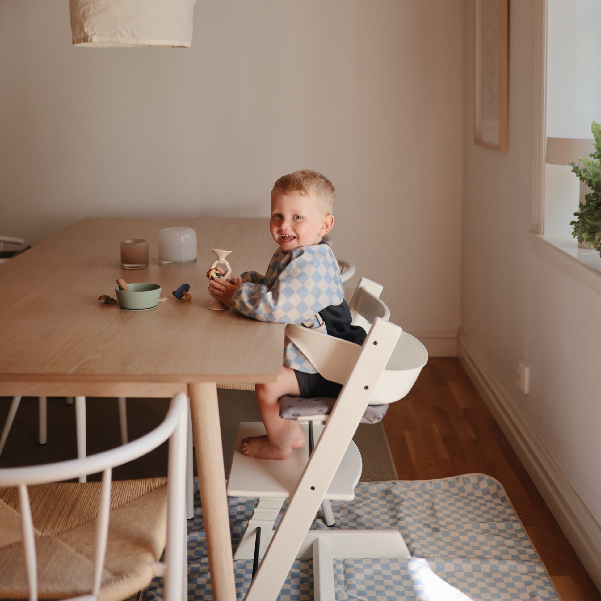 Child sitting in a high chair at a dining table in a home setting